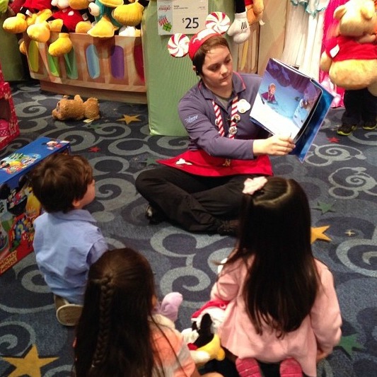 Tanayia reads a story to a group of children during storytime at Disney Store